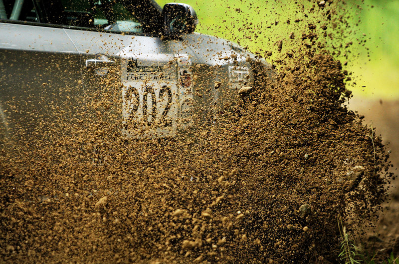 Dirt flies from a rally car as it navigates around a hairpin turn on the Newry race course.