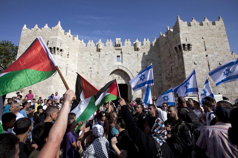 Israelis and Palestinians wave flags as Israelis celebrate Jerusalem Day in Jerusalem’s old city May 8. The U.S. on Sunday announced the resumption of Israeli-Palestinian talks.