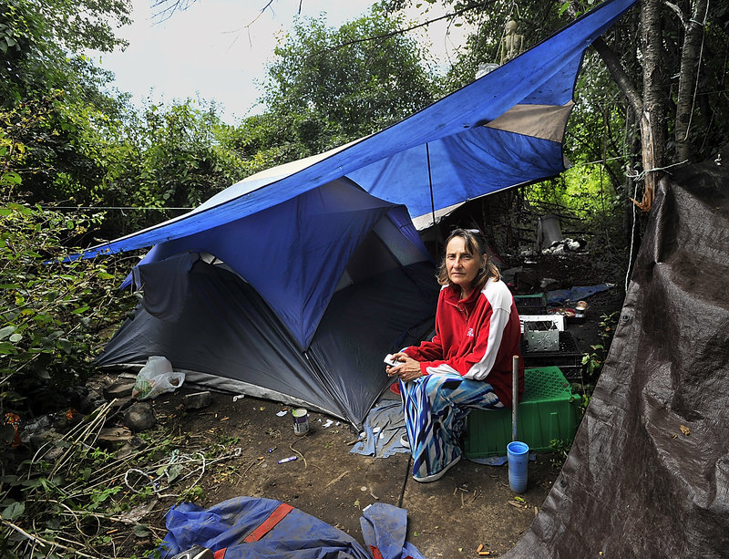 Anne M. Blake and life partner Kevin McBride have filed a lawsuit against the Westbrook Police Department saying they were illegally evicted from their apartment. In this Tuesday, July 30, 2013 photo she sits at a camp, which they built and now live in, near the Maine Turnpike at Exit 8.