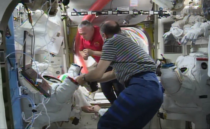 In this screen image from NASA video, astronauts aboard the International Space Station examine the spacesuit that was worn by Italian astronaut Luca Parmitano during a spacewalk that was aborted on Tuesday.