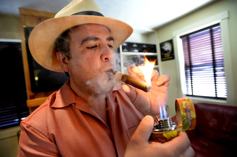 Daniel Vela, owner of Saco River Cigars on Middle Street in Saco, lights up a cigar in his lounge Wednesday. Vela believes a bottle club will complement the neighborhood because it will bring in people who are spending money at nearby restaurants and shops.
