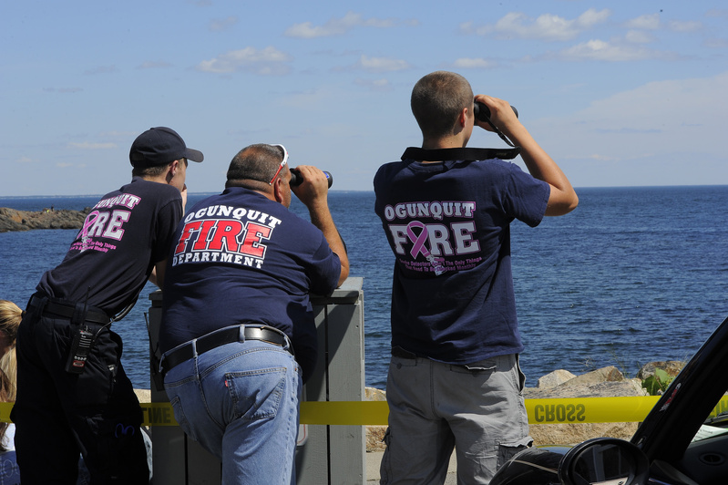 Tom Cryer, left, Gus Dunham and Jordan Moore of the Ogunquit Fire Department watch from shore Friday as searchers work the waters of Perkins Cove looking for a local fisherman who went missing Thursday night.