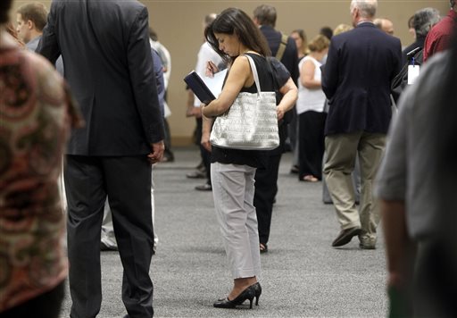 In this July 15, 2013 file photo, a woman waits to talk with employers at a job fair for laid-off IBM workers in South Burlington, Vt. The government issues the jobs report for July on Friday, Aug. 2, 2013.