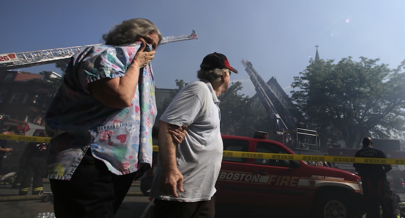 Janice Smythe covers her face as she walks through smoke with John Malone while passing a five-alarm blaze at St. John the Baptist Albanian Orthodox Church in South Boston on Wednesday.