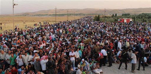 In this photo provided by the U.N. High Commissioner for Refugees and taken on Thursday, Aug. 15, 2013, Syrian refugees cross the border toward Iraq at the Peshkhabour border point at Dahuk, 260 miles northwest of Baghdad.