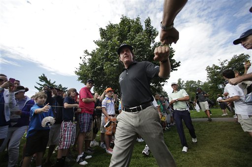 Phil Mickelson taps fists with a fan as he walks to the ninth tee during a practice round Tuesday for the PGA Championship golf tournament at Oak Hill Country Club in Pittsford, N.Y.