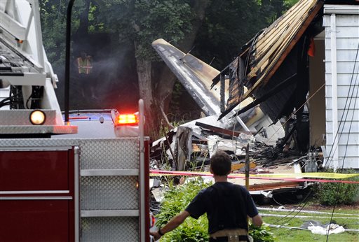 A firefighter surveys the scene of a small plane crash Friday in East Haven, Conn. The multi-engine, propeller-driven plane plunged into a working-class suburban neighborhood near Tweed New Haven Airport, on Friday.