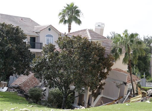 A portion of a building rests in a sinkhole Monday in Clermont, Fla. The sinkhole, 40 to 50 feet in diameter, opened up overnight and damaged three buildings at the Summer Bay Resort.