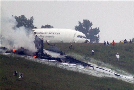 Debris burns as a UPS cargo plane lies on a hill at Birmingham-Shuttlesworth International Airport in Birmingham, Ala., about a half-mile north of Runway 18.