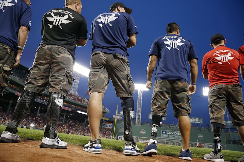In this Aug. 18, 2013 file photo, members of the Wounded Warrior Amputee Softball Team, made up of active soldiers and veterans who were wounded in service, are given recognition prior to a baseball game between the Boston Red Sox and New York Yankees at Fenway Park in Boston. (AP Photo/Michael Dwyer)