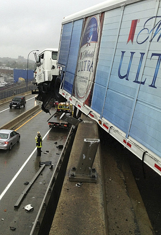 A beer delivery truck hangs off Interstate 93 over the Leverett Connector highway ramp after striking a guardrail Friday in Boston.