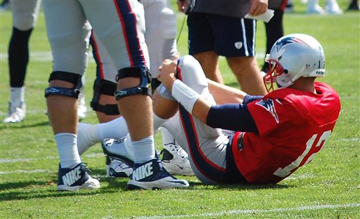 Quarterback Tom Brady grabs his left knee after an apparent injury Wednesday during a joint workout with the Tampa Bay Buccaneers at training camp in Foxborough, Mass.
