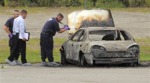 Police investigate a vehicle that burned before dawn Monday, Aug. 13, 2012, off Target Industrial Circle in Bangor, Maine. After the fire was extinguished, three bodies were found inside the parked car. One of two southern New England men charged with killing three Maine residents last year and then setting fire to a car containing the bodies told investigators that one victim pleaded for her life before being shot. (AP Photo/Bangor Daily News, Gabor Degre)