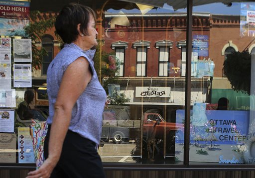 A shopper strolls past a storefront in downtown Ottawa, Ill., recently. Although consumers are more confident about the future, their assessment of the current economy dipped slightly in August.