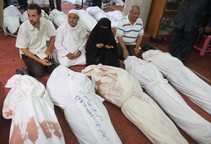 People mourn sitting next to bodies of supporters of ousted President Mohammed Morsi at the El-Iman mosque in Cairo's Nasr City, Egypt, Thursday, Aug. 15, 2013. Egyptian authorities on Thursday significantly raised the death toll from clashes the previous day between police and supporters of the ousted Islamist president, saying hundreds of people died and laying bare the extent of the violence that swept much of the country and prompted the government to declare a nationwide state of emergency and a nighttime curfew. (AP Photo/Ahmed Gomaa)