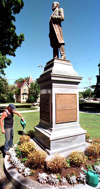 A parks department worker waters flowers at the base of the Thomas Goodall statue in Sanford's Central Park in this 1997 file photo.