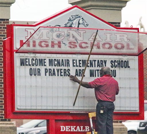 A McNair High school staff member works on a welcome sign for Ronald E. McNair Discovery Learning Academy students on Wednesday, a day after an armed gunman held staff members captive and fired into the floor of the school office. As officers swarmed the campus outside, he shot at them at least a half a dozen times with an assault rifle from inside the school and they returned fire.