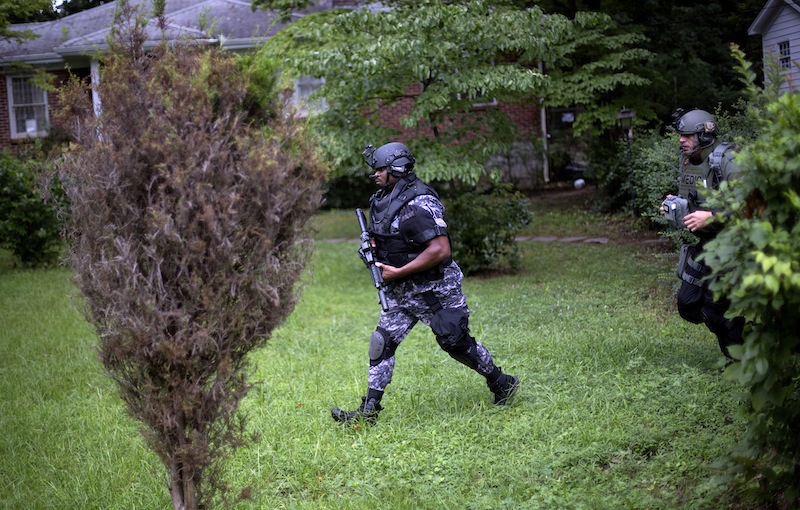 Dekalb County Police SWAT officers run though the front yard of a home toward Ronald E. McNair Discovery Learning Academy after reports of a gunman entered the school, Tuesday, Aug. 20, 2013, in Decatur, Ga. Superintendent Michael Thurmond says all students at Ronald E. McNair Discovery Learning Academy in Decatur east of Atlanta are accounted for and safe Tuesday and that he is not aware of any injuries. (AP Photo/David Goldman)