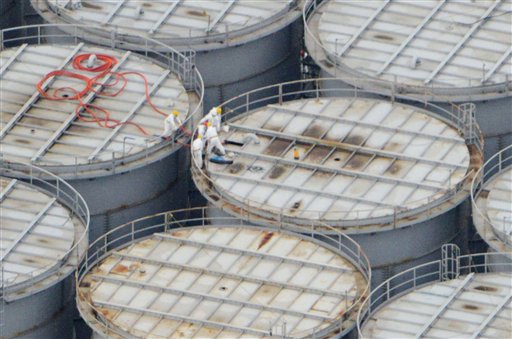In this Tuesday aerial photo, workers stand on one of the hundreds of steel storage tanks at Japan's crippled atomic power plant in Fukushima prefecture, northern Japan. The operator of the plant says about 80,000 gallons of contaminated water have leaked from one of the tanks.