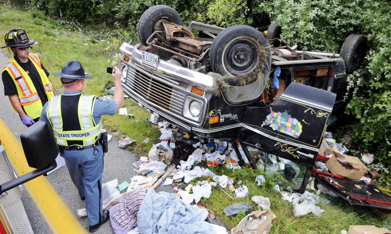 Maine State Trooper Dane Wing photographs a van with Augusta firefighter/paramedic Sean Estabrook on Tuesday Aug. 13, 2013. An I-95 crash killed the occupant after the van rolled over on the offramp for exit 112A in Augusta.