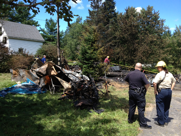 Investigators from the Office of the State Fire Marshal and Richmon police examine the remnants of a mobile home that burned Sunday night on Kimball Street in Richmond.