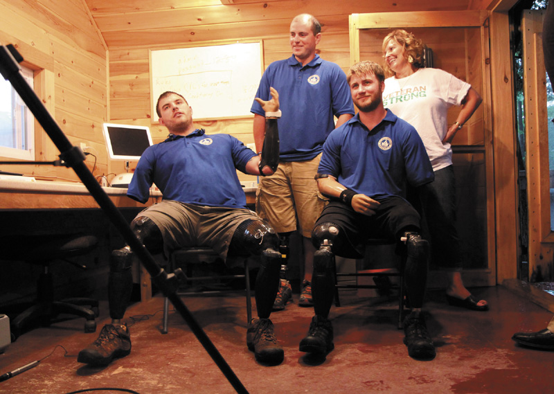 Quadruple amputee Travis Mills, left, talks to reporters with fellow wounded veterans Taylor Morris, right, and Drew Mullee, top, as Maine's First Lady Ann LePage looks on at Camp Kennebec in Belgrade on Wedneday night. This week is "Founder's Week" at the Travis Mills Project National Veterans' Family Center at the camp located on the shores of Salmon Lake.