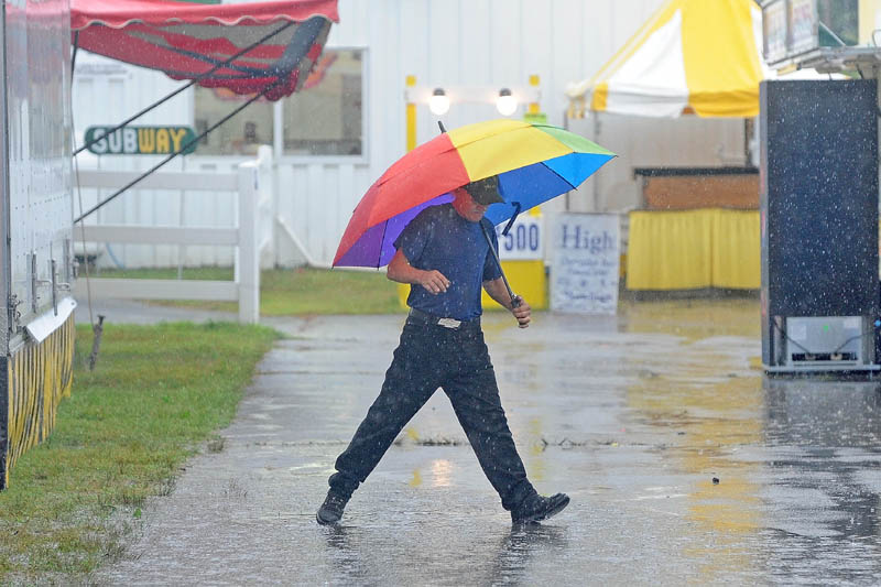 Tom Cowdry, of Oxford, tries to avoid a puddle as he walks around the 195th annual Skowhegan State Fair at the Skowhegan Fairgrounds on Friday. Cowdry, a 16-year ride operator at the Skowhegan State Fair, wound up playing bingo with other ride operators, as steady rain forced the rides to shut down.