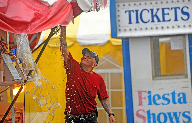 Staff photo by Michael G. Seamans Eddie Cote, a worker with Andrew's Concessions, clears the tents of standing waters rain falls on the 195th annual Skowhegan State Fair at the Skowhegan Fairgrounds on Friday.