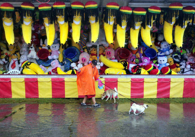 Carol Deshenes walks with her dogs, Cote and Princess, as rain falls on the 195th annual Skowhegan State Fair at the Skowhegan Fairgrounds today.