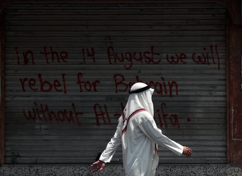 A Bahraini man walks past a closed shop sprayed with graffiti against the ruling Al Khalifa family in the western village of Karzakan, Bahrain, Wednesday, Aug. 14, 2013. Opposition groups launched a fresh push against the Gulf monarchy on Wednesday, an effort to revitalize their two-and-a half-year-old pro-democracy uprising. (AP Photo/Hasan Jamali)