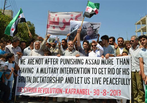 This citizen journalism image provided by Edlib News Network, ENN, shows anti-Syrian regime protesters carrying a banner during a demonstration in Kafr Nabil town, in Idlib province, northern Syria, on Friday, Aug. 30, 2013.