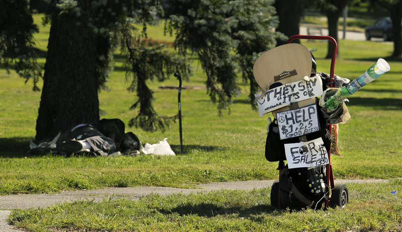 A homeless man named Joe, who declined to give his last name, sleeps in the shade in Deering Oaks Park on Friday, August 16, 2013, behind his prop to collect change at the corner of Marginal Way and Forest Avenue. Joe made the prop in response to the city's new ordinance that prohibits panhandling in medians.