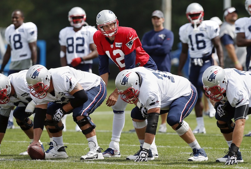New England Patriots quarterback Tom Brady (12) waits for a snap behind the offensive line during NFL football practice in Foxborough, Mass., Monday, Aug. 19, 2013. (AP Photo/Michael Dwyer)