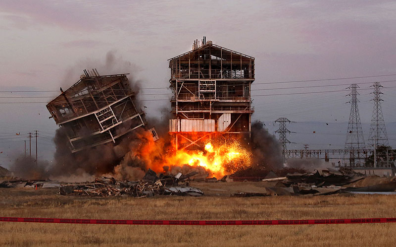 One of the remaining towers comes down Saturday at the decommissioned Kern Power Plant in Bakersfield, Calif. Five spectators were injured, including a man whose leg was severed, when shrapnel was sent flying, police said. More than 1,000 people had gathered at 6 a.m. in a nearby parking lot to watch the planned implosion. PGE Implosion