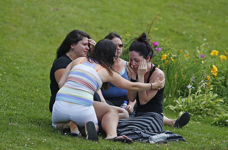 A woman comforts her friend while they sit on the grass at the Polyvalente Montignac, the school sheltering the people who were forced to leave their houses after the explosion, in Lac Megantic, July 7, 2013. Nearly 50 people died in the crash and 30 buildings were destroyed. (REUTERS/Mathieu Belanger) :rel:d:bm:GF2E9771BAG01