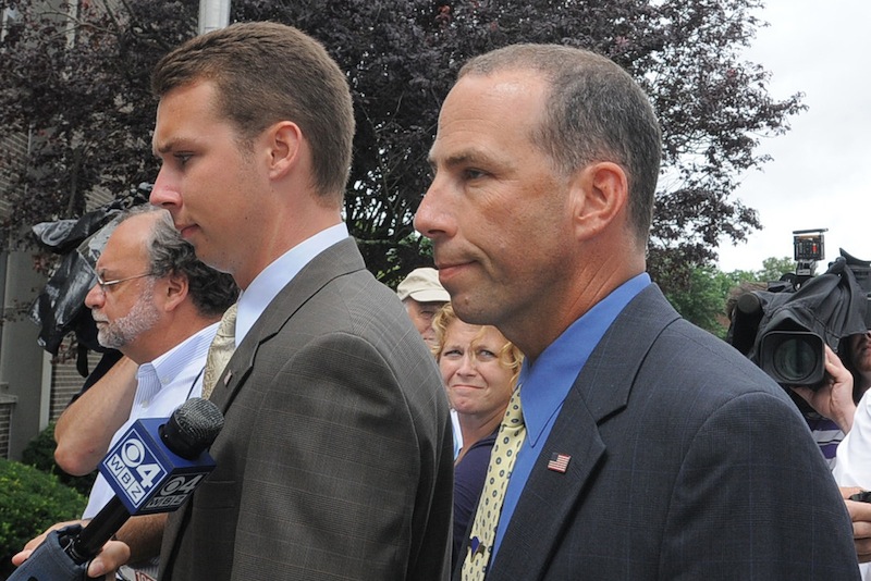Massachusetts State Police Sgt. Sean Murphy, right, a tactical photographer, and his son Connor Patrick Murphy, arrive at State Police Headquarters for his hearing to determine his duty status after he released images of the arrest of the Boston Marathon bombing suspect, in Framingham, Mass., Tuesday July 23, 2013. Following a status hearing at state police headquarters, Murphy was placed on desk duty, where he won't have contact with the public, until a further investigation is completed, according to state police spokesman David Procopio. (AP Photo/The Boston Herald, Ted Fitzgerald) BOSTON OUT