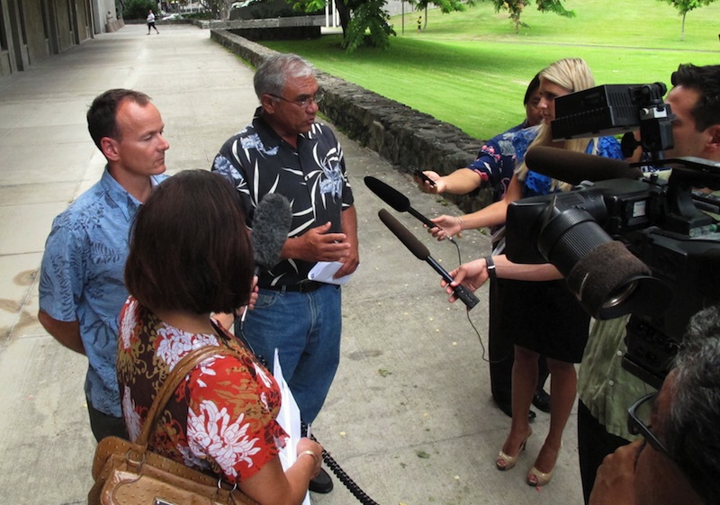 Chairman William Aila of the Hawaii Department of Land and Natural Resources, center, speaks to reporters at a news conference in Honolulu on Tuesday, Aug. 20, 2013. Hawaii officials plan to spend the next two years studying tiger shark movements around Maui amid what they call an unprecedented spike in overall shark attacks since the start of 2012. (AP Photo/Oskar Garcia)