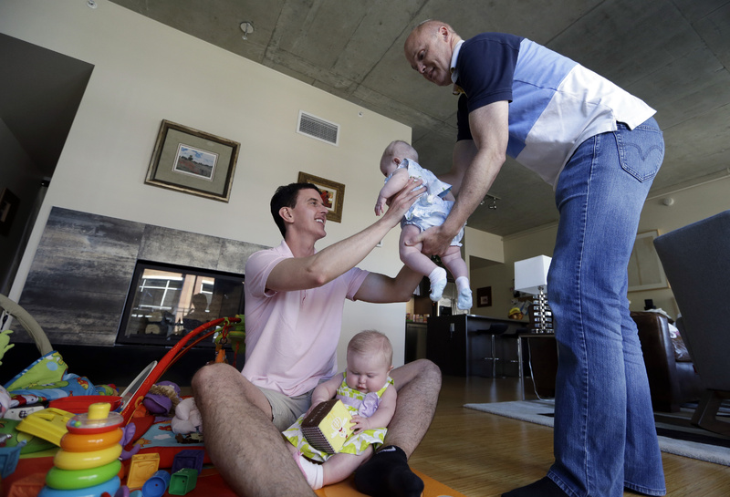 Nanny Randy Hambley, right, hands Trey Powell his daughter, Kylan, as her twin sister, Ashton, sits in his lap at their home in Seattle. "I just wanted to be a dad. Time was not on my side, and I didn't have the luxury of waiting for an ideal mate," Powell said.