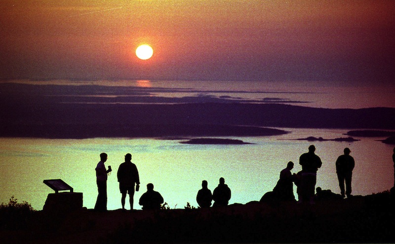 In this September 1999 file photo, visitors to Acadia National Park watch the sunrise from the summit of Cadillac Mountain near Bar Harbor, Maine, one of the first places on the East Coast to see the sun appear. Mount Desert Island, which is linked to mainland Maine by a two-lane bridge, is ranked 25th in Travel & Leisure magazine’s article, “World’s Best Islands." (AP Photo/Robert F. Bukaty)