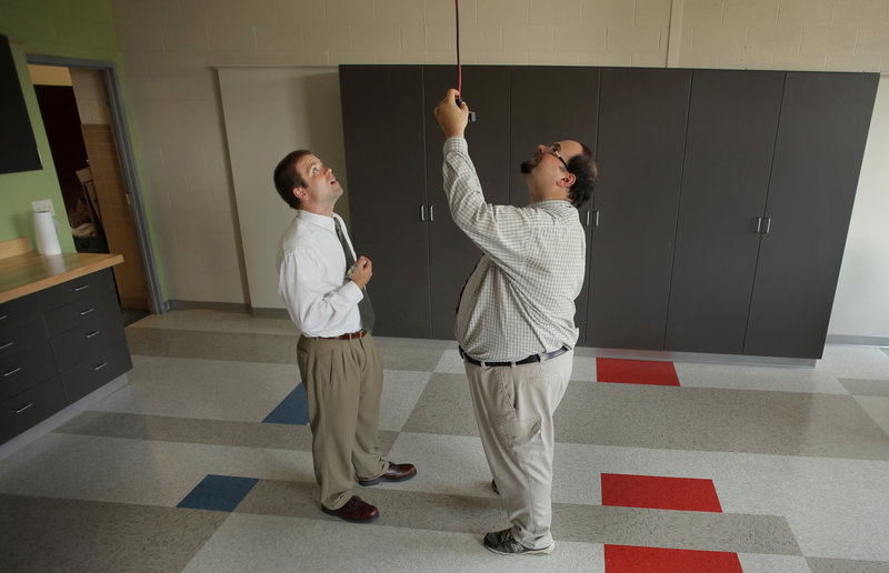 Jonathan Whitehead, left, an engineering teacher at Thornton Academy, and fellow Physics teacher Matthew Amoroso, at right, test out the drop extension cords in the school's new STEM lab, unveiled Wednesday, August 21, 2013.
