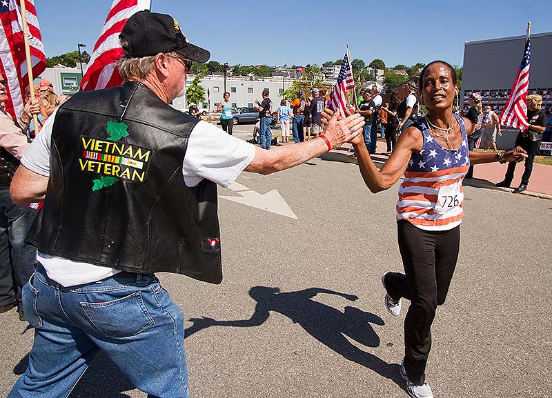 Vietnam veteran Jim Merrill of Auburn gives a high-five to a finisher of the sixth annual Run for the Fallen Maine in Portland on Sunday.