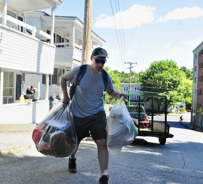 Peter Coltart carries bags of belonging towards a taxi as he moves out of 9 Laurel St. in Augusta on Friday August 23, 2013.