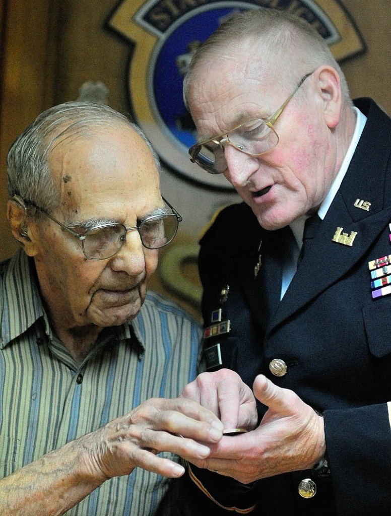 World War II veteran Al Kramer, of South China, left, and Peter W. Ogden, Director of the state's Bureau of Veterans' Services, look at a commemorative coin given to Kramer by Ogden during a cermeony on Thursday August 29, 2013 from Rep. Mike Michaud in Augusta.