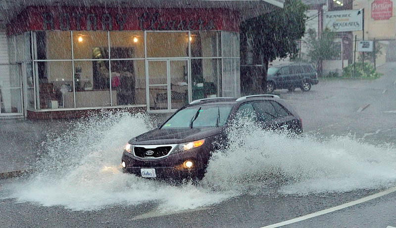 A car splashes through a large puddle during a morning downpour today in front of Rotary Cleaners, near where Western Avenue ends at the Memorial Circle. Heavy rain overwhelmed storm drains and caused minor street flooding in several areas of the city.