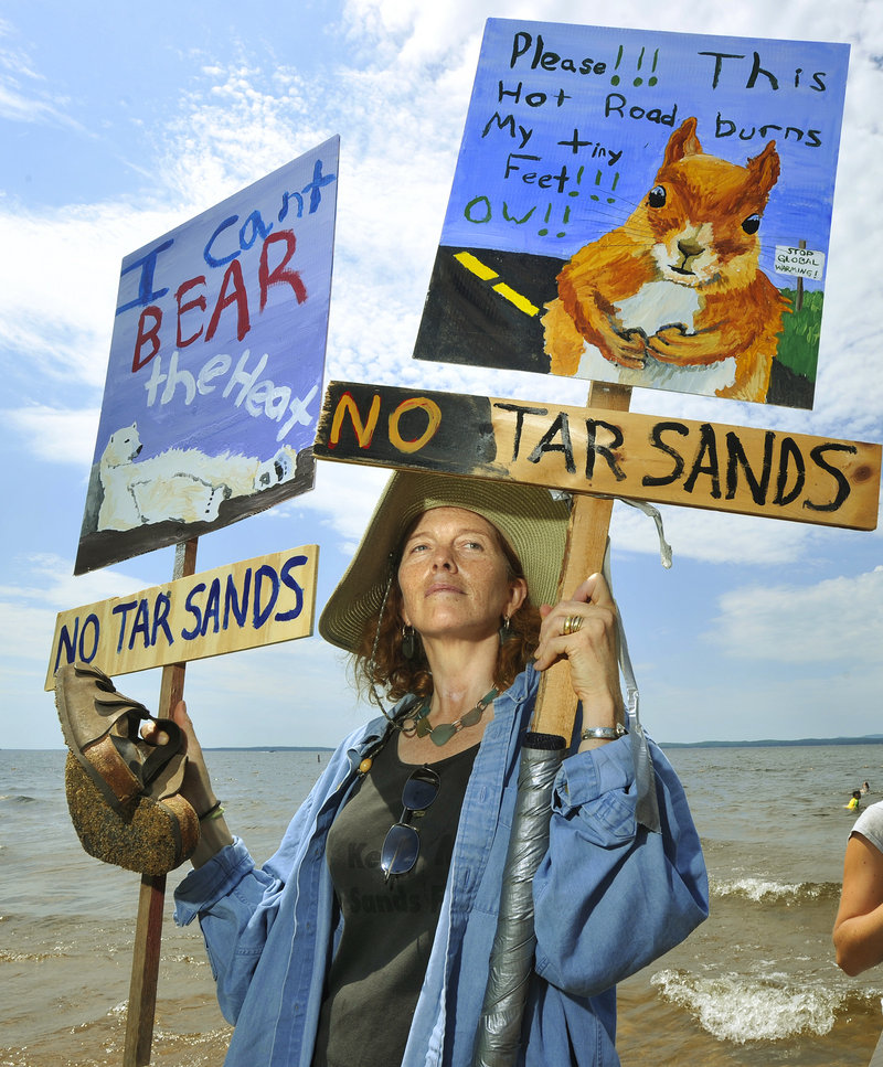 A protester holds anti-tar sands posters at a Sebago Lake State Park rally in July. Leaders at the highest levels should say "no" to tar sands pipelines both nationally and locally, two Maine Guides write.