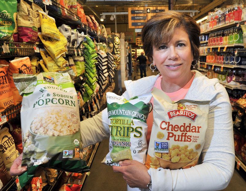 Barbara Gulino of Whole Foods in Portland holds some of the hundreds of products with labels indicating they’re non-genetically modified, certified organic or locally produced.