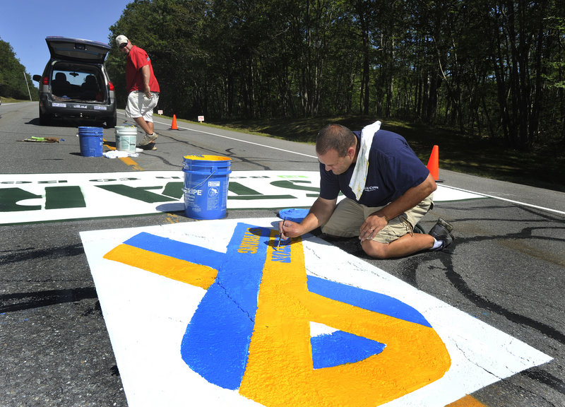 Matt Tobin and Jeremy Gardner paint the starting line area on Route 77 in Cape Elizabeth on Wednesday morning in preparation for Saturday’s Beach to Beacon road race. The “Boston Strong” ribbon is an addition this year to support the city and the marathon bombing victims.