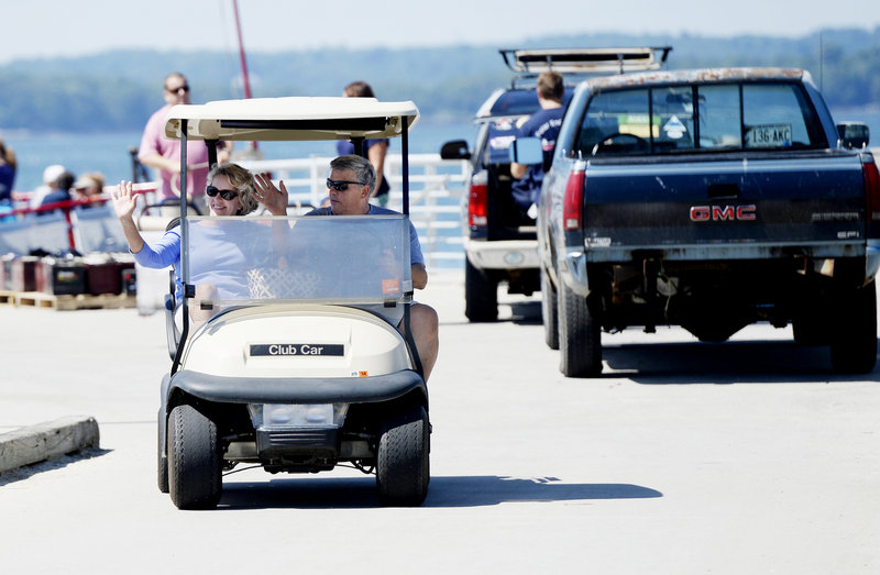 Camille and Wes Wolfertz of Long Island wave as they drive their golf cart away from the Long Island dock after a trip to the mainland for supplies Thursday, August 1, 2013.