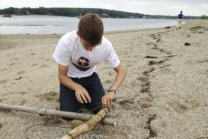 Galen DuBois of Woolwich ties together tree limbs as he begins to build a raft that will be used to help “rescue” him and 20 other students from Little Chebeague Island.