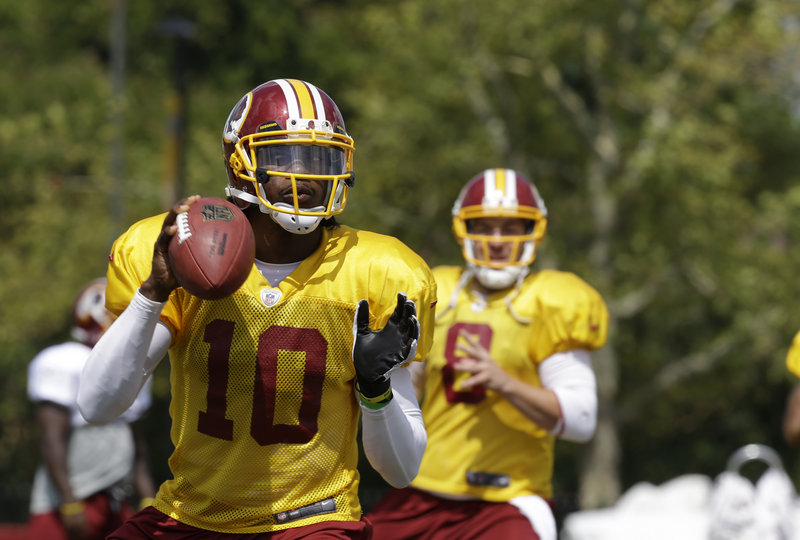 Robert Griffin III looks for a receiver Friday while working out with the Washington Redskins during an afternoon session at training camp in Richmond, Va.